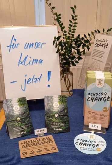 „Für unser Klima – jetzt!“ Schild mit GEPA ChocoChange Produkten.